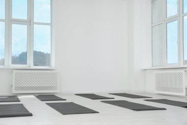 Egzersiz paspasları ve büyük pencereleri olan geniş yoga stüdyosu.