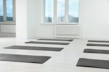 Yerde spor paspasları olan geniş bir yoga stüdyosu.
