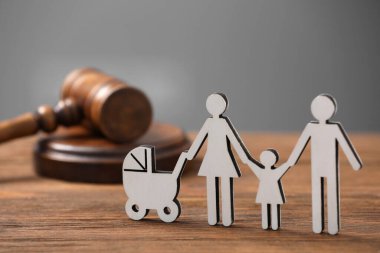 Aile hukuku. Çocuklu ebeveyn figürü ve tahta masada tokmak.