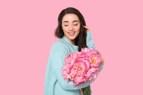 ピンクの背景に牡丹の花束を持つ美しい若い女性 — ストック写真