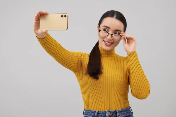 Χαμογελαστή Νεαρή Γυναίκα Που Παίρνει Selfie Smartphone Γκρι Φόντο — Φωτογραφία Αρχείου