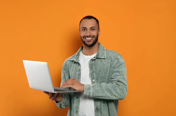 Sonriente Joven Que Trabaja Con Ordenador Portátil Sobre Fondo Naranja — Foto de Stock