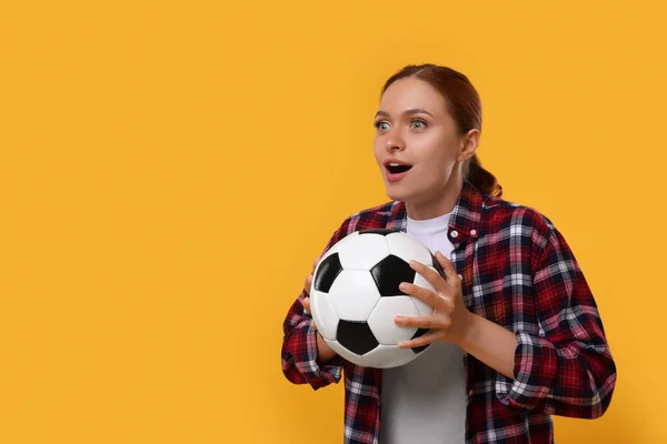 Emotional fan holding football ball on yellow background, space for text
