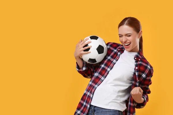 Emotional fan holding football ball and celebrating on yellow background, space for text