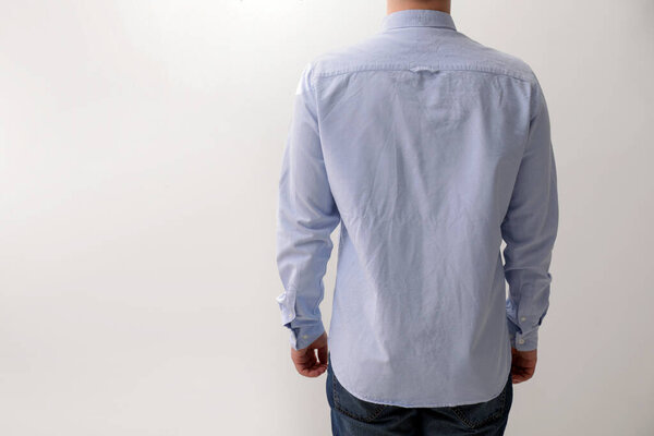 Man wearing rumpled shirt on white background, back view