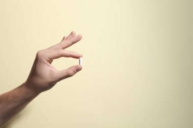 Bej arka planda hapları tutan adam, yakın plan. Metin için boşluk