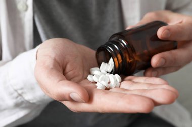 Hapları şişeden döken adam, yakın çekim görüntüsü.