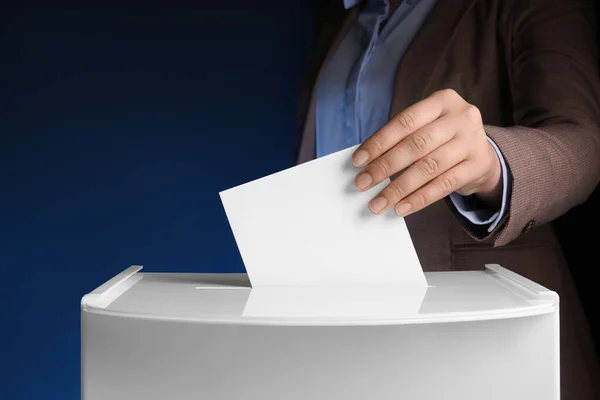 ダークブルーの背景に投票ボックスに彼女の投票を置いた女性 クローズアップ — ストック写真
