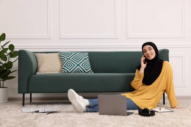 Tesettürlü Müslüman bir kadın odada dizüstü bilgisayarla konuşuyor. Metin için boşluk