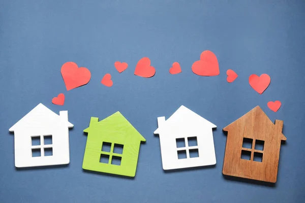 Long-distance relationship concept. House models and paper hearts on blue background, flat lay