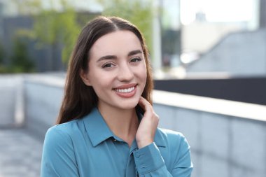 Açık havada güzel bir kadının portresi. Çekici bir bayan gülümseyip kameraya bakıyor.