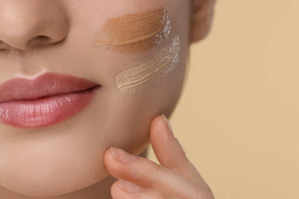 stock image Woman with swatches of foundation on face against beige background, closeup