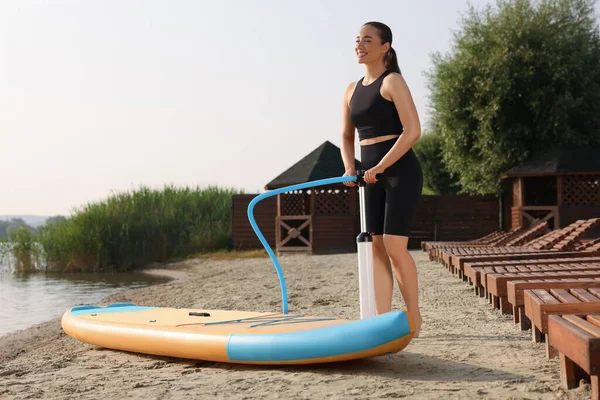 川岸でSupボードをポンプアップする女性 — ストック写真