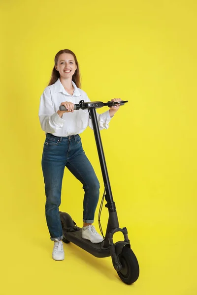 黄色の背景にモダンな電動キックスクーターを持つ幸せな女性 — ストック写真