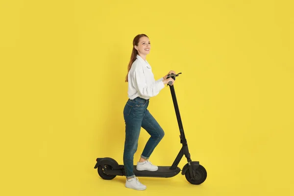 Sarı Arka Planda Modern Elektrikli Scooter Kullanan Mutlu Bir Kadın — Stok fotoğraf