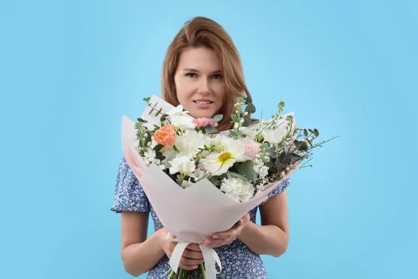 明るい青の背景に花の花束を持つ美しい女性 — ストック写真