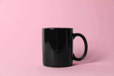 Pembe arka planda siyah bir seramik bardak.