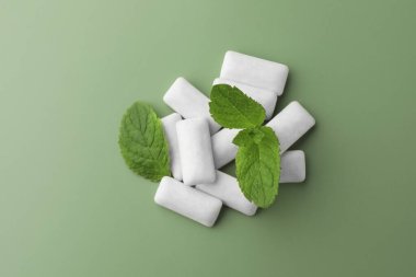 Lezzetli beyaz sakız ve nane yaprakları açık yeşil arka planda, üst görünümde.