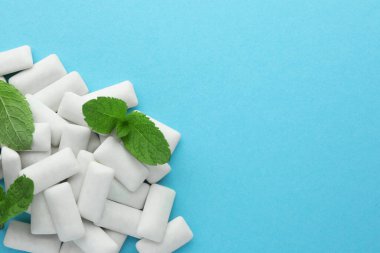 Açık mavi arka planda lezzetli beyaz sakız ve nane yaprakları yığını, üst manzara. Metin için boşluk