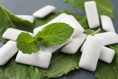 Tasty white chewing gums and mint leaves on grey background, closeup clipart