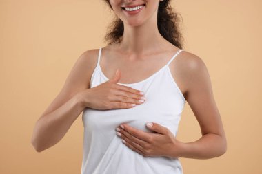 Woman doing breast self-examination on light brown background, closeup clipart