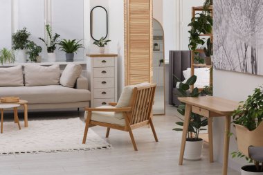 Farklı saksı yeşili bitkiler ve rahat kanepesi olan şık bir oda. İç tasarım