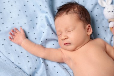 Sevimli yeni doğmuş bebek yatakta uyuyor, yakın plan.