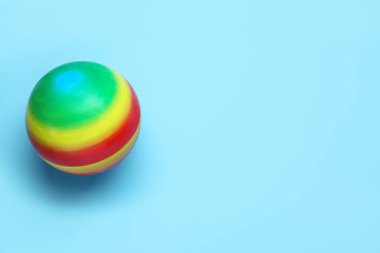 Açık mavi arka planda parlak lastik çocuk topu, üst manzara. Metin için boşluk