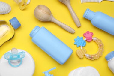 Sarı arka planda bebek bakım ürünleri ve aksesuarlarıyla düz konum