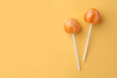 Turuncu arka planda leziz lolipoplar, düz yatış. Metin için boşluk