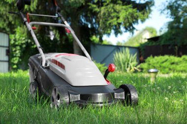 Bahçedeki yeşil çimlerin üzerinde çim biçme makinesi, metin için yer