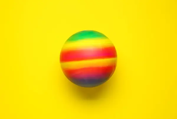 黄色の背景に明るいゴム製子供のボール トップビュー — ストック写真
