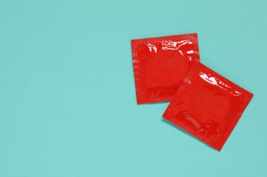 Turkuaz arka planda kondom paketleri, düz konum ve metin için boşluk. Güvenli seks.