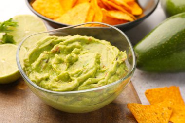 Masada cips ve limonla servis edilen bir kase lezzetli guacamole.