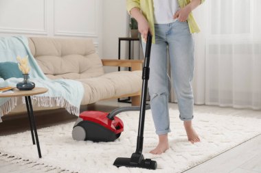 Halıyı elektrikli süpürgeyle temizleyen kadın, yakın çekim.