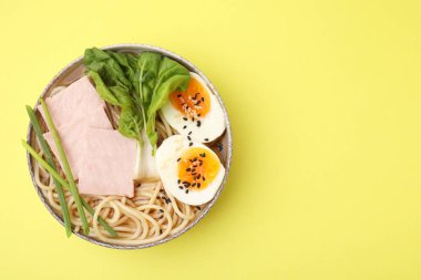 Soluk sarı arka planda etli ramen, üst manzara ve yazı için yer. Erişte çorbası.