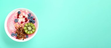 Tahıllı meyve suyu kasesi, turkuaz arka planda kivi ve böğürtlen, üst manzara. Metin için alanı olan pankart tasarımı