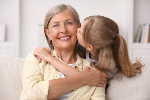 Счастливая внучка целует бабушку дома