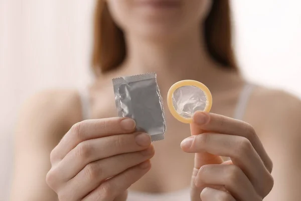 屋内で包まれないコンドームを持っている女性 クローズアップ 安全なセックス — ストック写真