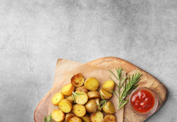 带有香味迷迭香和酱汁的美味烤土豆放在灰色纹理桌子上 案文的篇幅 — 图库照片