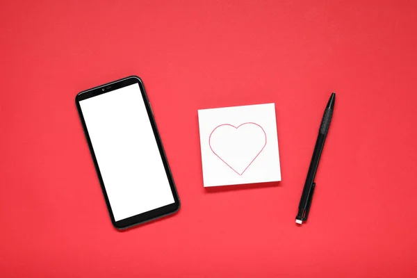 Long-distance relationship concept. Smartphone, love note and pen on red background, flat lay