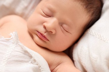 Cute newborn baby sleeping on white blanket, closeup