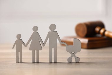 Aile hukuku. Çocuklu ebeveyn figürü ve tahta masada tokmak.