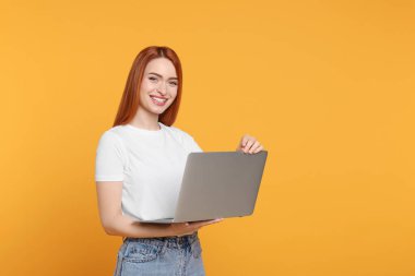 Sarı arka planda dizüstü bilgisayarı olan gülümseyen genç kadın, mesaj için boşluk
