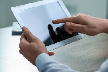 Ahşap masada tablet kullanan adam, yakın plan.