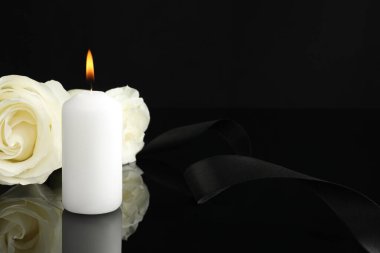 Yanan mum, beyaz güller ve siyah ayna yüzeyinde kurdele karanlıkta, yazı için yeri olan yakın plan. Cenaze sembolleri