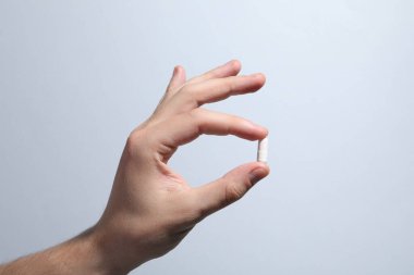 Açık gri arka planda hapları tutan adam, yakın plan.