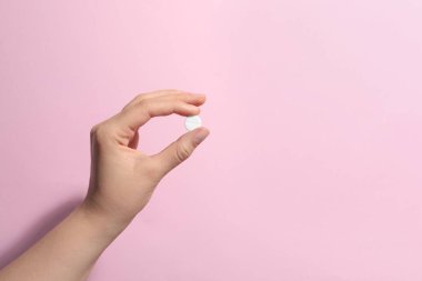 Pembe arka planda hapları tutan kadın, yakın plan. Metin için boşluk