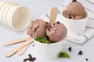 Kağıt bardaklar, beyaz fayanslı masada lezzetli çikolatalı dondurma, yakın plan.
