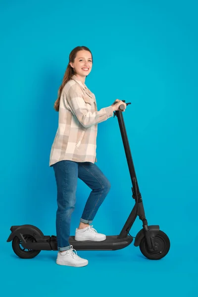 穿着浅蓝色背景的现代电动踏板车的快乐女人 — 图库照片